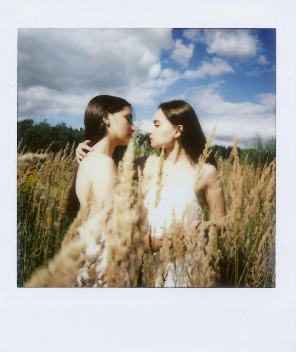 two girls with long hair are standing in a grassy field