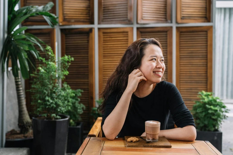 a woman sitting at a table with her hand on her face smiling