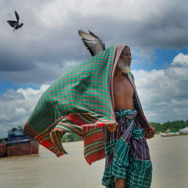 man in green cloth and bird under blue cloudy sky