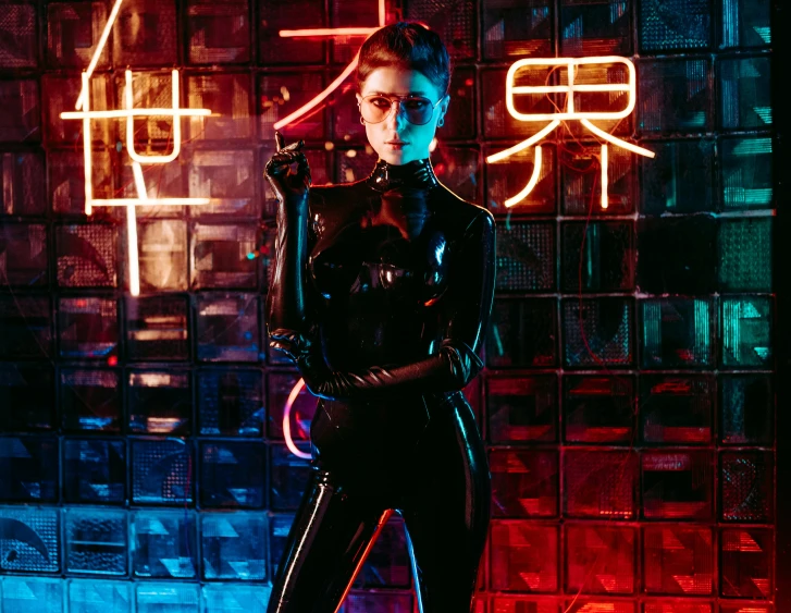 a woman in black standing next to glass and neon lights