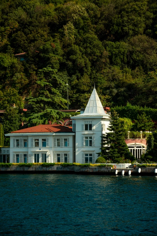 a large white building on the water near a house