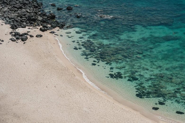 the view from above shows several stones and corals in the water and on top of the sandy shore