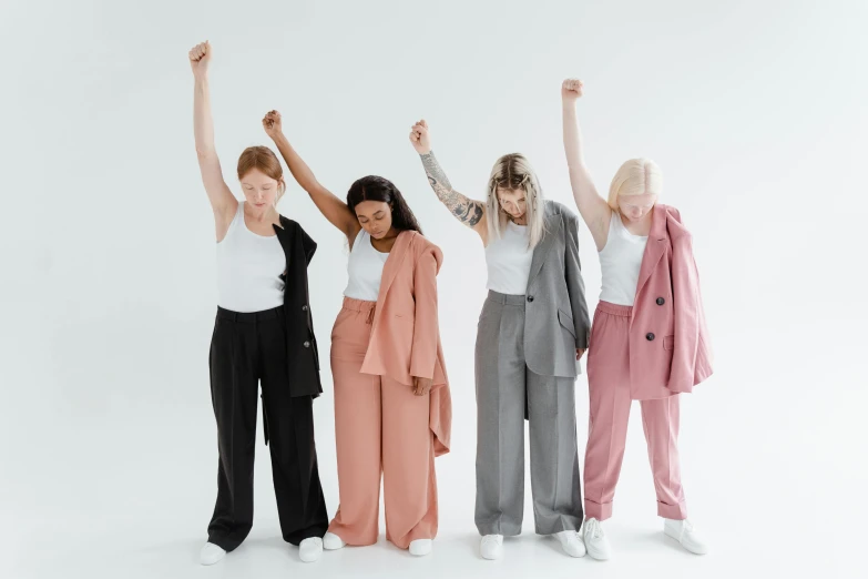 four women standing next to each other with arms raised