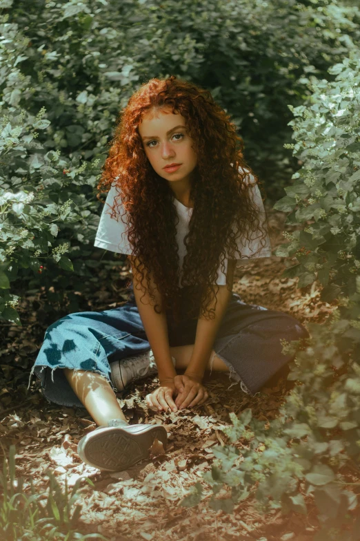 a girl with red curly hair sitting on the ground