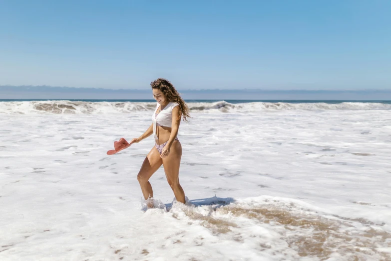 a girl in a bikini plays in the waves at a beach