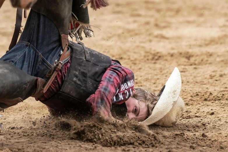 a cowboy falling to the ground on his bucking bronco
