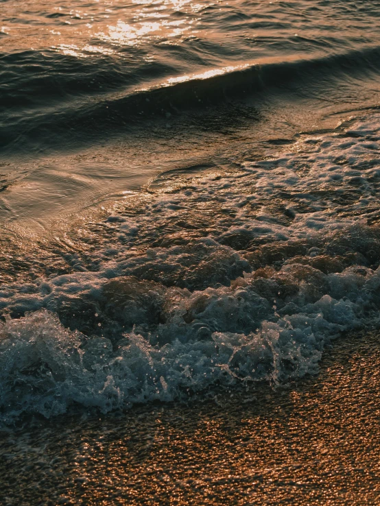 some water waves are hitting the shore and a bright light in the background