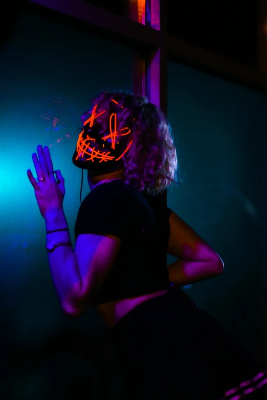 woman in neon mask standing against green light