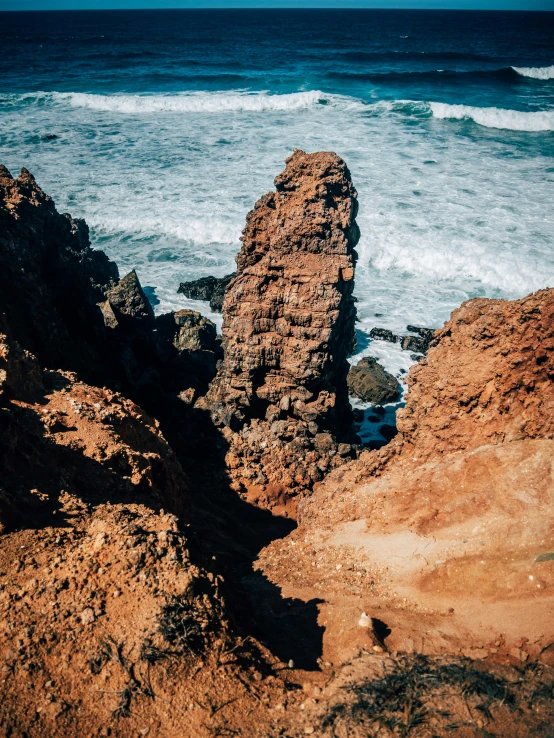 two rocks next to the ocean with one rock sticking out