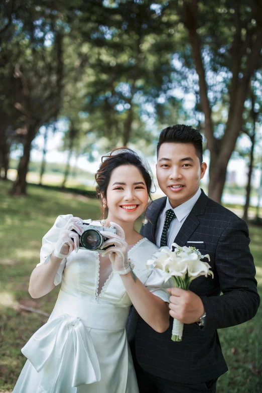 bride and groom taking a picture with camera in park