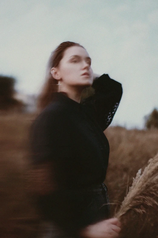 a girl walking through a field with her arms raised