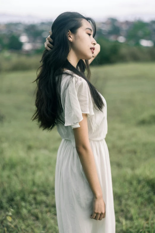 a woman standing in a field with her hair blowing in the wind