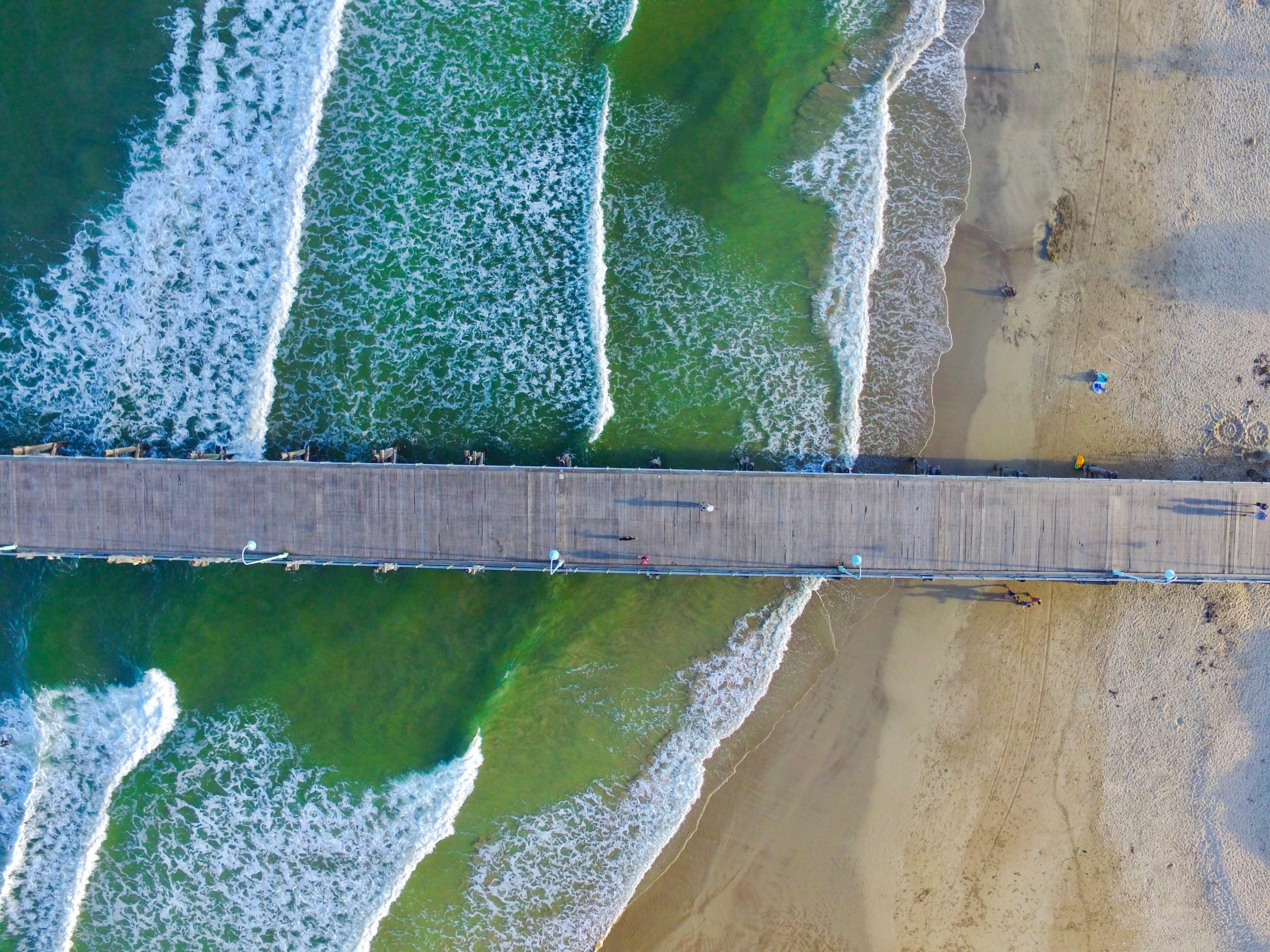 a pier over the beach surrounded by waves