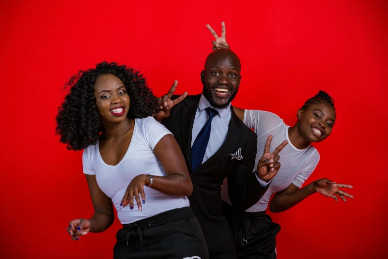 a man, woman and young man wearing black clothing making the peace sign