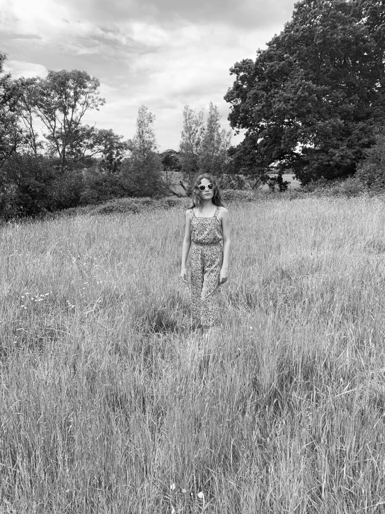 woman in a long dress is standing on the grass