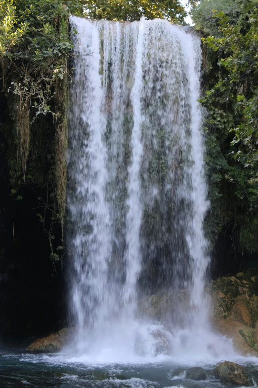 a waterfall near some trees and water