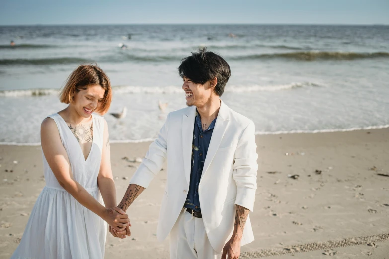 the young couple is walking on the beach holding hands