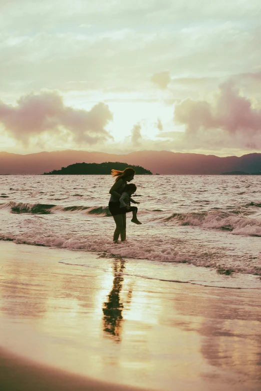 two people walking on the beach at sunset