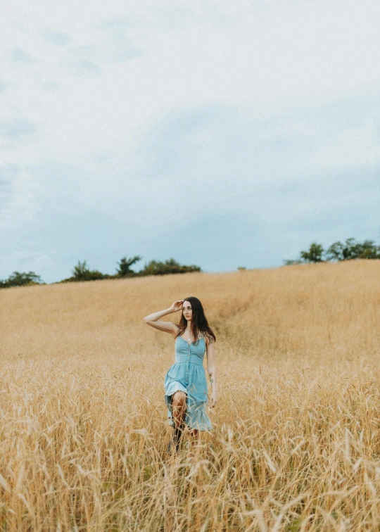 a woman is walking through a field holding her hat