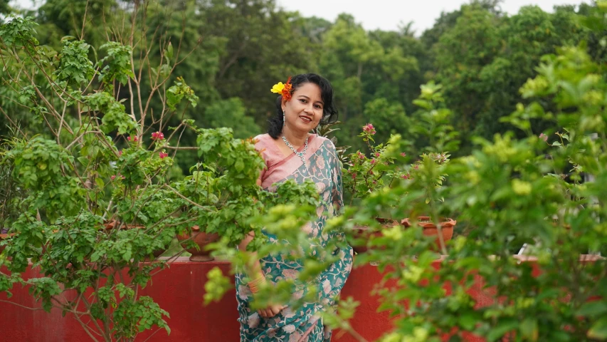 a woman in a floral dress standing among bushes