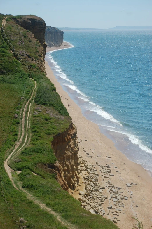 a beach that is next to some water and a hill