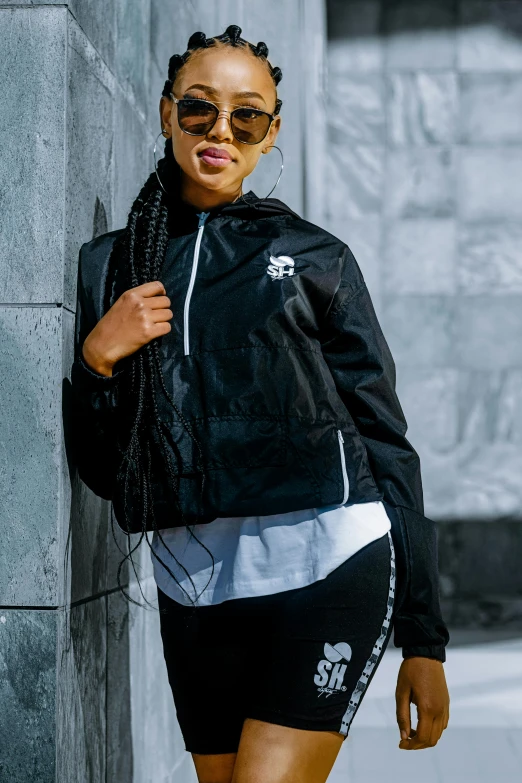 a woman with glasses leaning on a building and smiling