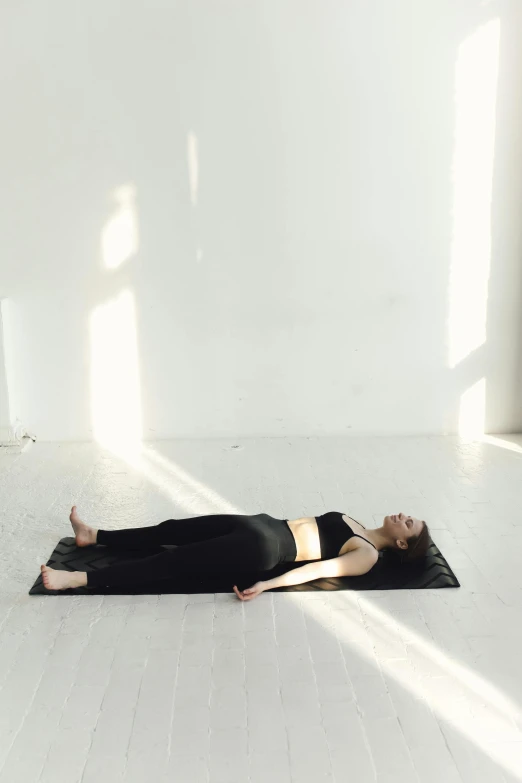 a woman in black laying on her back while wearing a leg pad
