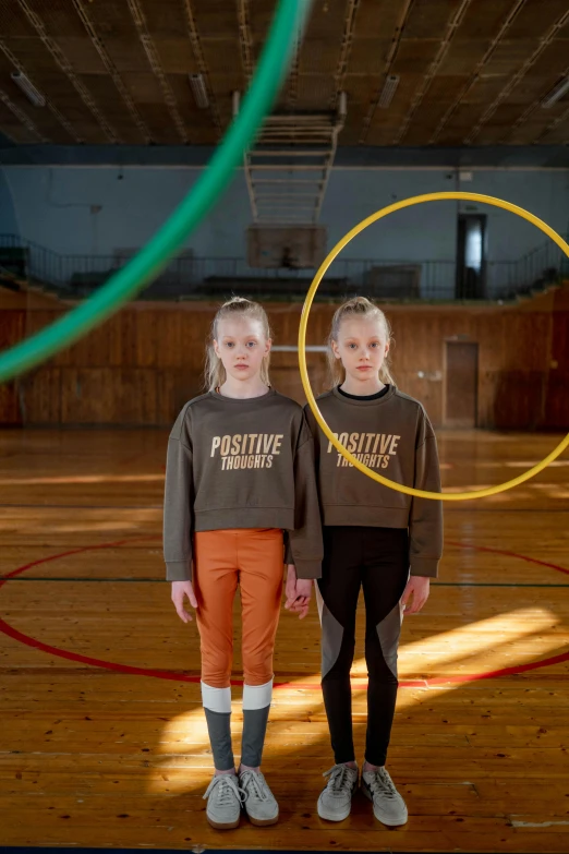 two children standing in a gymnasium in front of large hoop