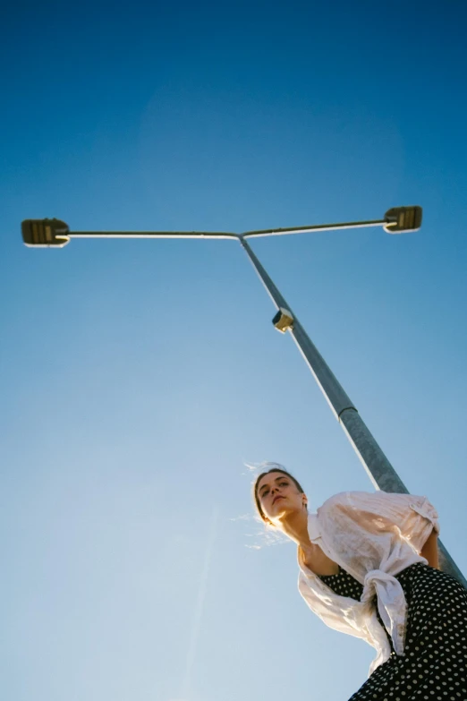 a woman standing on top of a pole under a street light