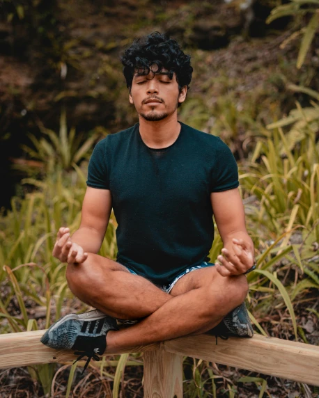 a man sitting in a yoga position on a wooden bench