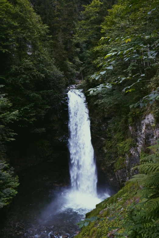 a tall waterfall flowing down a lush green hillside