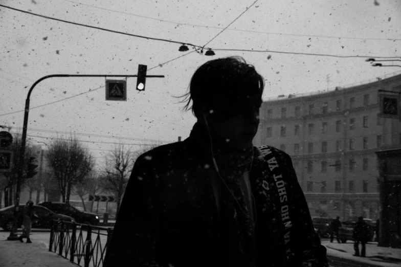 black and white pograph of man with dark hair walking down a street