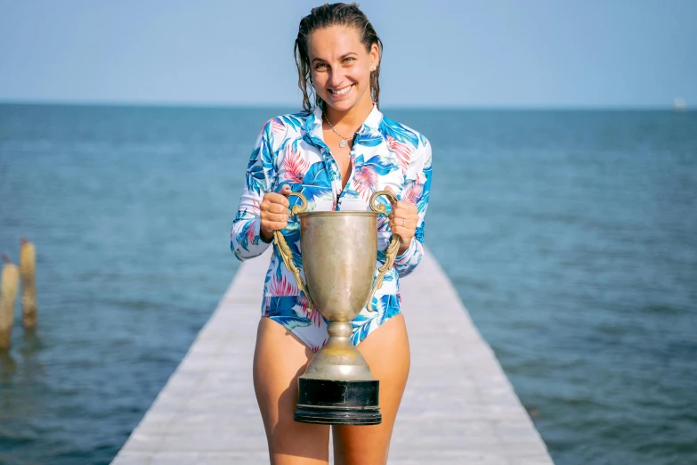 a female in a blue shirt holding a silver trophy