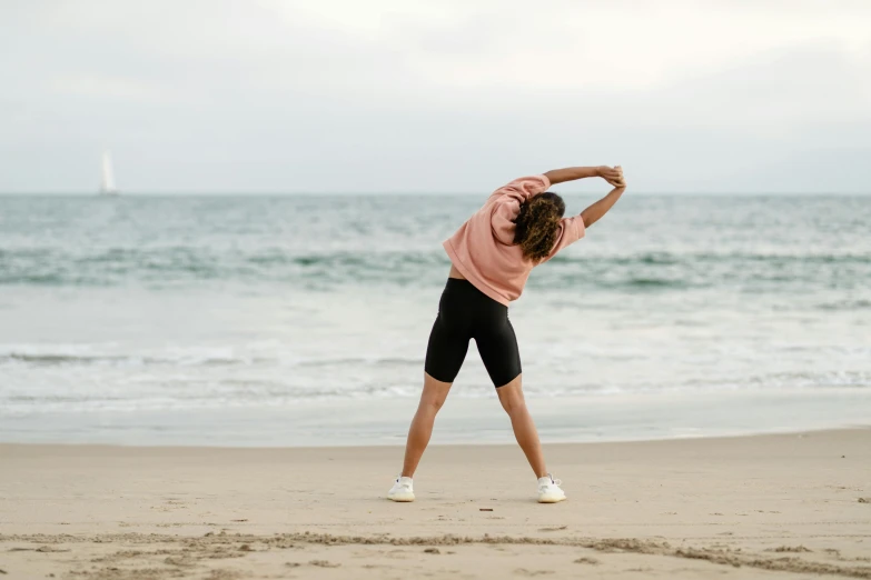 a woman stretching on the beach with her arms outstretched