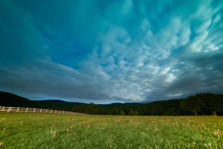 an open pasture with a wooden fence and mountains in the distance