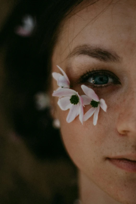 the face of a woman with flowers pinned to her forehead