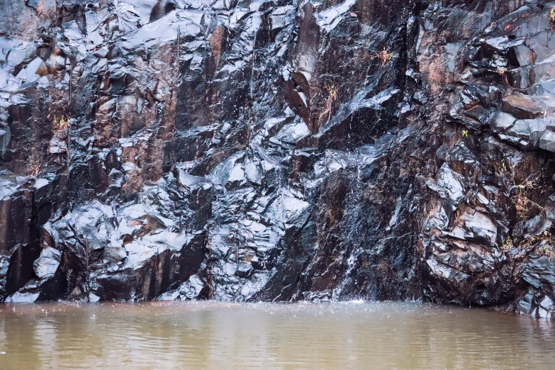 water and rocks in the snow and a bird standing on a dock