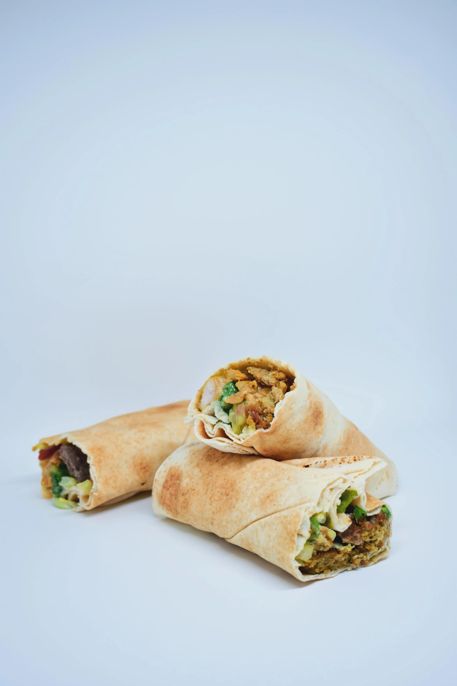 two wrap sandwiches on a white background with a focus on one