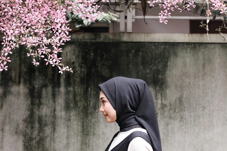 a woman walking down a street in front of pink flowers