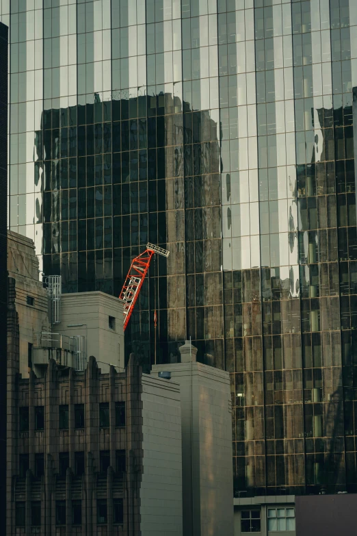 reflection of a very tall building with a red ladder being lifted into it