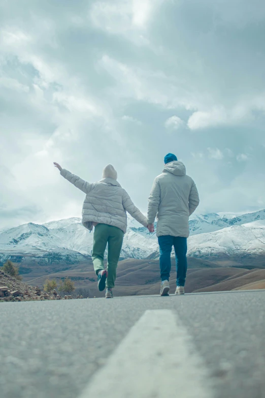 two people walking down the road towards mountains