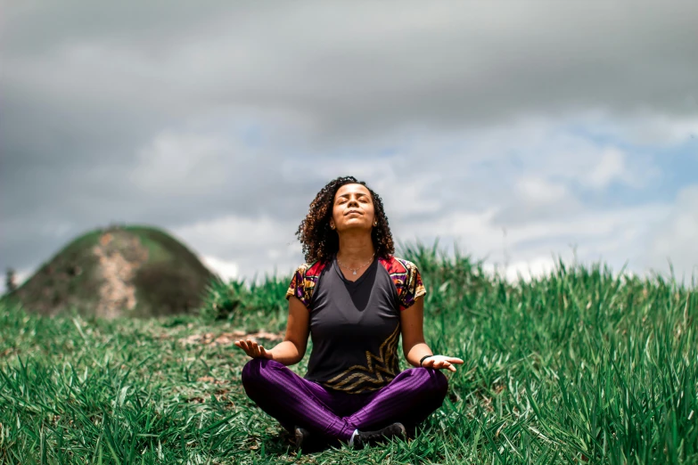 a person meditating on a grassy hill