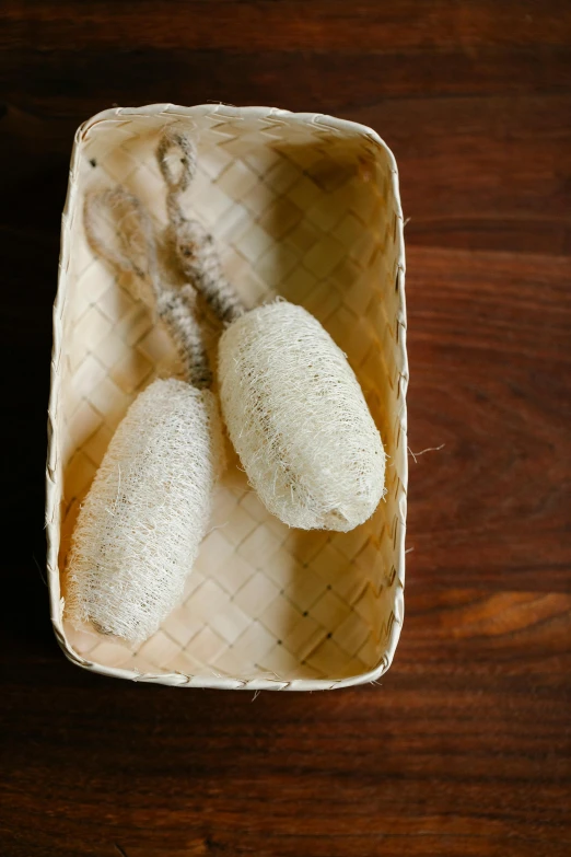 two white balls of some sort in a basket on a table