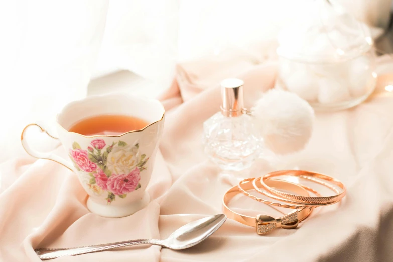 a cup and some gold rings near a bottle of alcohol