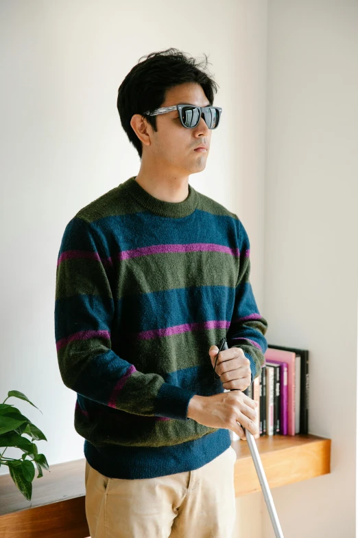 man in striped sweater standing next to book shelf