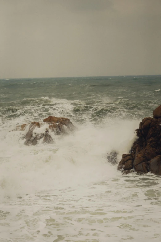 a person walking through choppy water next to rocks