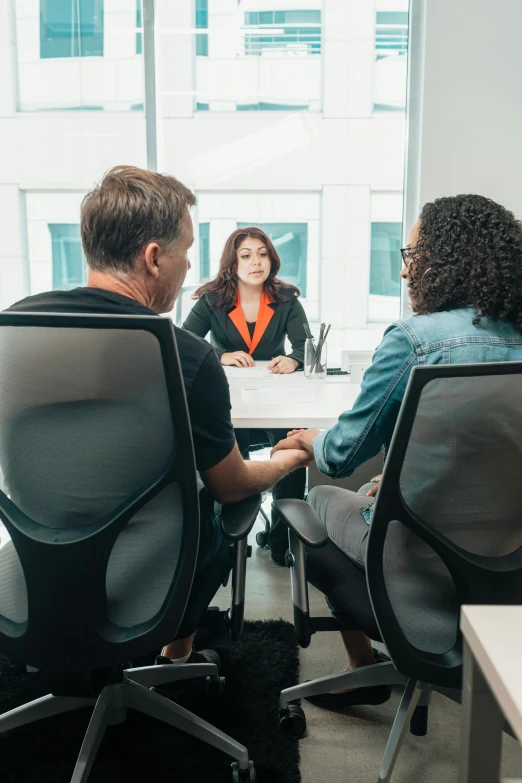 a man sitting at a desk with two woman