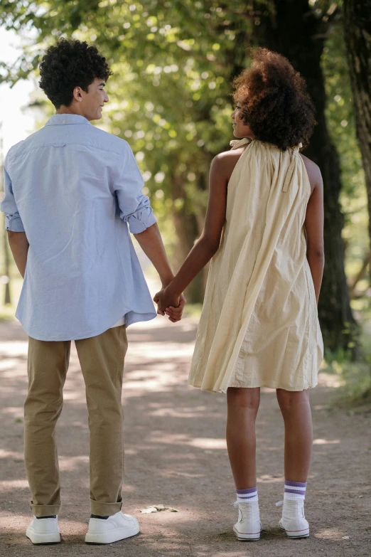 two young people holding hands while standing on a path in a park