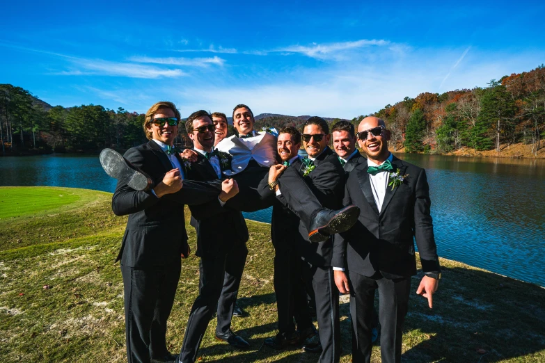 several men posing together near a lake