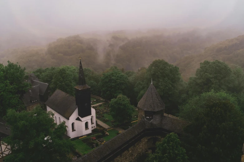 an aerial view of a church and trees in the fog